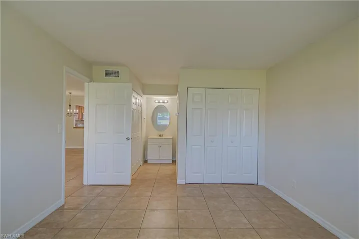 Unfurnished bedroom featuring light tile patterned floors, a closet, and a chandelier