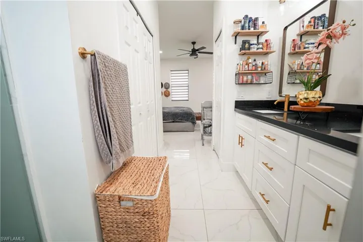 Ensuite bathroom with marble finish floors, vanity, and a ceiling fan