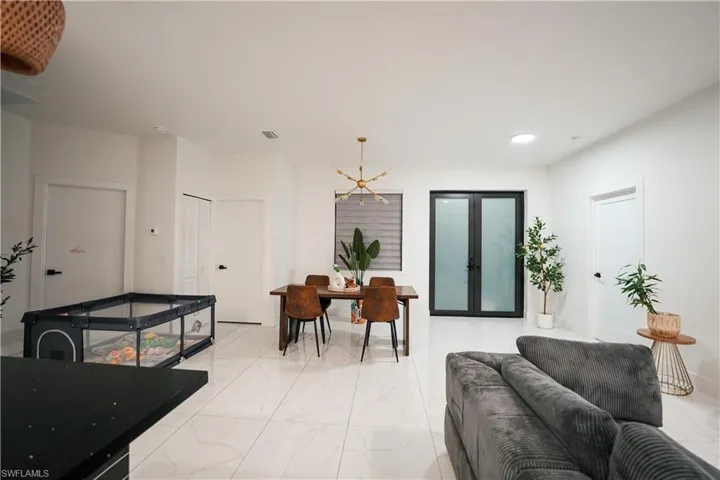 Living room with light marble finish floors, french doors, a chandelier, and recessed lighting