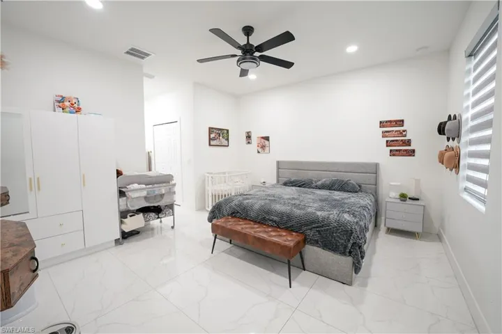Bedroom with light marble finish floors, recessed lighting, and ceiling fan