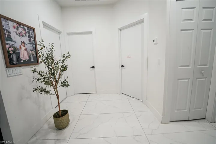 Hallway featuring light marble finish floors and baseboards