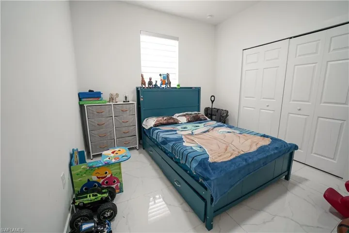 Bedroom featuring marble look tiles and a closet