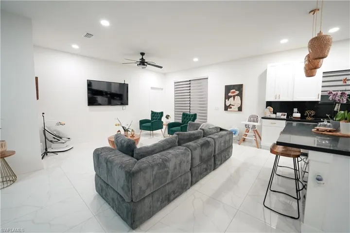 Living area featuring light marble finish floors, recessed lighting, a ceiling fan, and built in study area