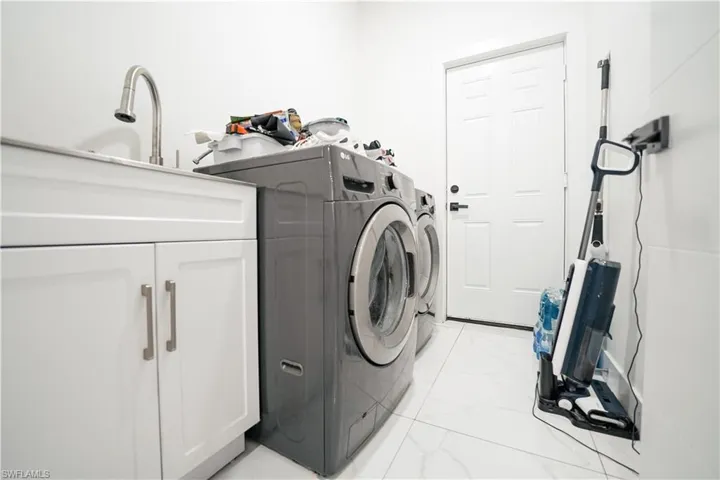 Washroom featuring cabinet space, independent washer and dryer, and light marble finish flooring