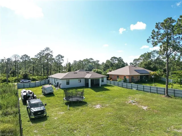Fenced backyard featuring a trampoline and view of wooded area