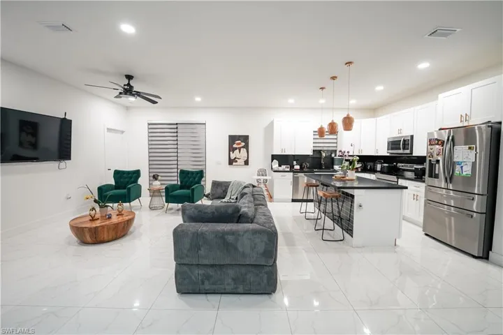 Living area with recessed lighting, light marble finish floors, and a ceiling fan