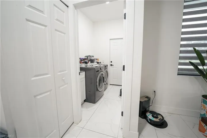 Laundry area featuring independent washer and dryer, light marble finish flooring, and cabinet space