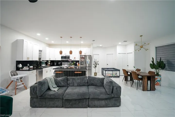 Living room featuring light marble finish flooring, recessed lighting, and a chandelier
