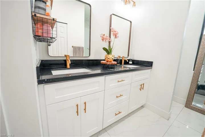 Full bathroom with marble finish floors and double vanity