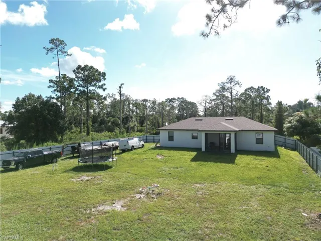 Fenced backyard featuring view of scattered trees