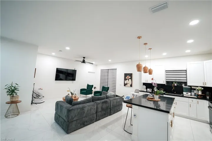 Living area with a ceiling fan, light marble finish flooring, and recessed lighting