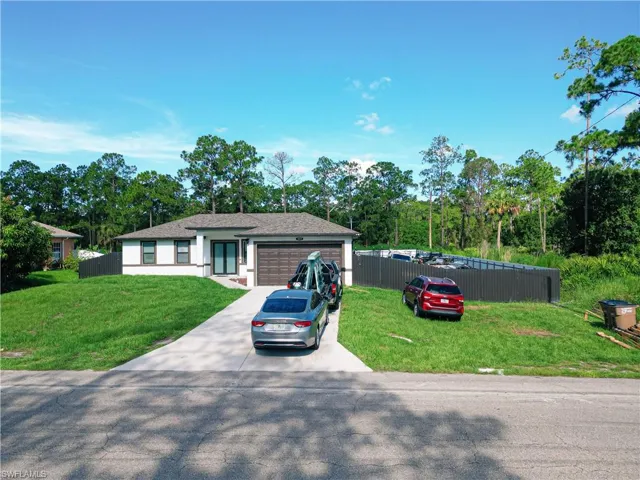 Ranch-style home with a garage, driveway, and view of scattered trees