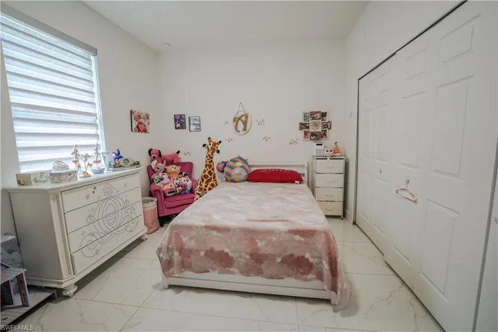 Bedroom with light marble finish floors and a closet