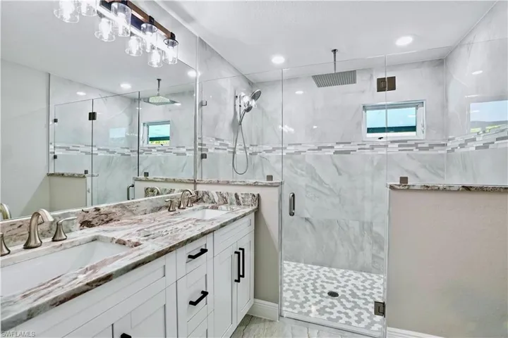Bathroom with a walk in shower, double vanity, and plenty of natural light