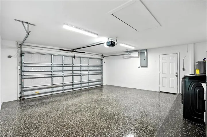 Garage with washer / clothes dryer, electric panel, and a garage door opener