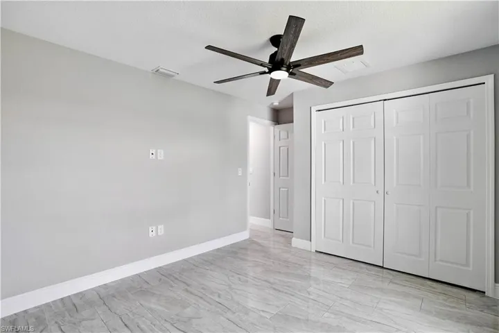 Unfurnished bedroom featuring a ceiling fan and a closet with wood shelving