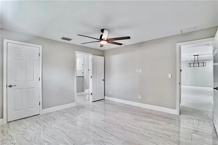 Unfurnished bedroom with ensuite bath and ceiling fan