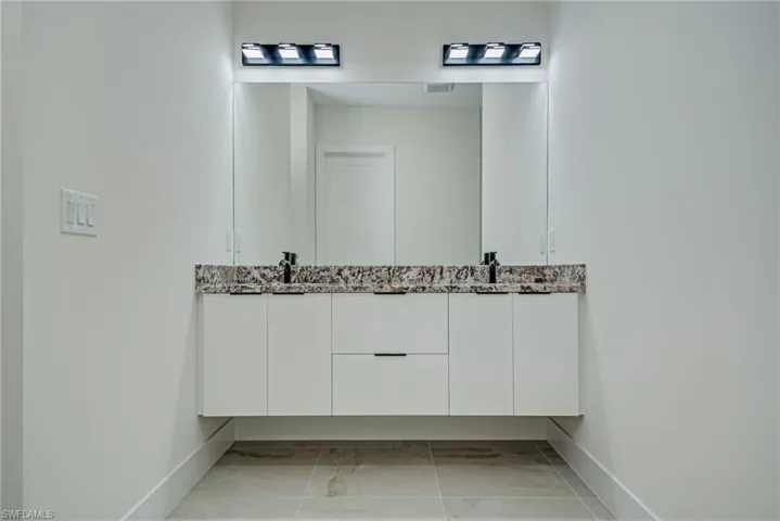 Bathroom with double vanity and baseboards