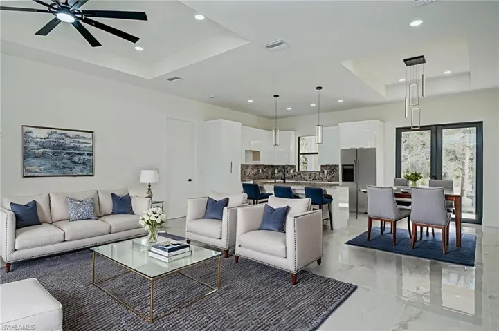 Living room featuring a tray ceiling, a ceiling fan, and recessed lighting