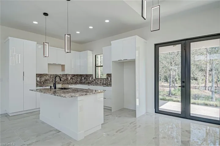 Kitchen featuring backsplash, light stone countertops, white cabinets, pendant lighting, and recessed lighting