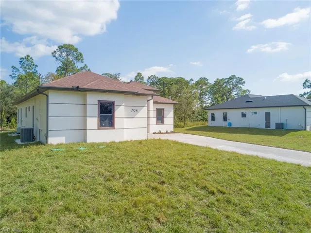 View of side of home with a lawn and a central AC unit