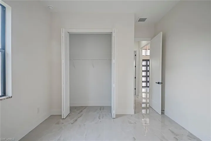 Unfurnished bedroom with light marble finish flooring and a closet