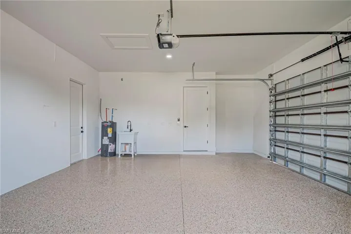 Garage with water heater, a garage door opener, and recessed lighting