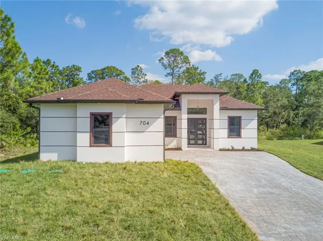 View of front of home featuring a front lawn, stucco siding, french doors, and a shingled roof