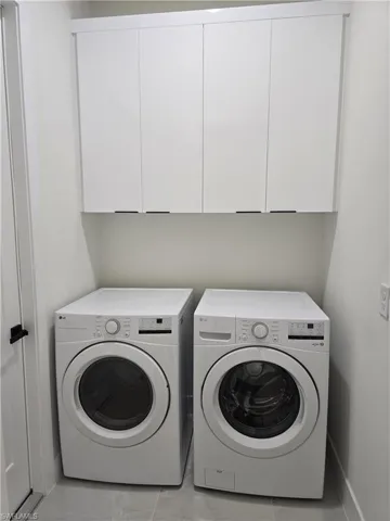 Laundry room featuring cabinet space, separate washer and dryer, and tile patterned flooring