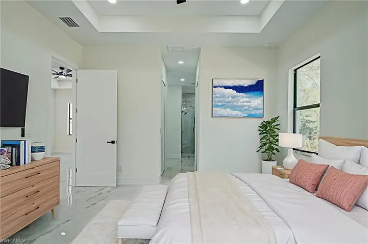 Bedroom with recessed lighting, a tray ceiling, and ensuite bath