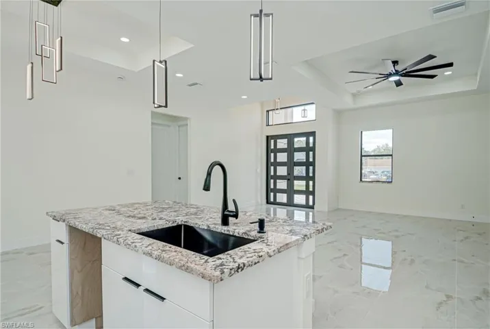 Kitchen featuring a tray ceiling, white cabinetry, light stone countertops, decorative light fixtures, and recessed lighting