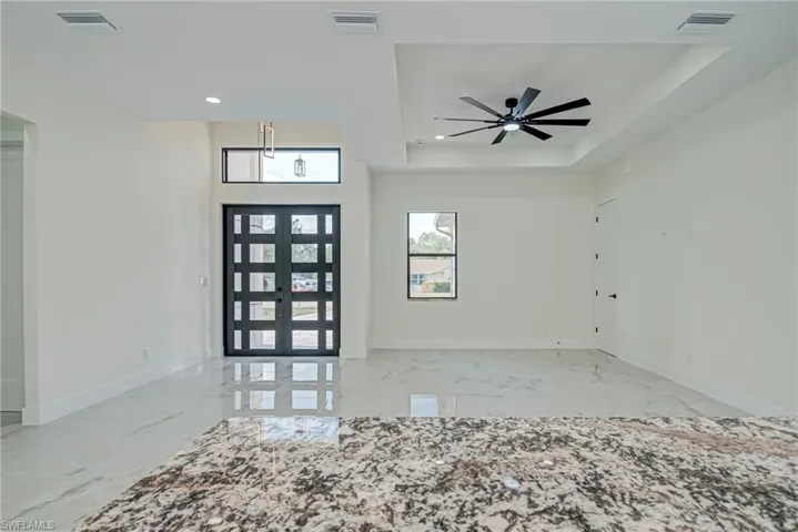 Entryway featuring french doors, light marble finish floors, a raised ceiling, recessed lighting, and a ceiling fan