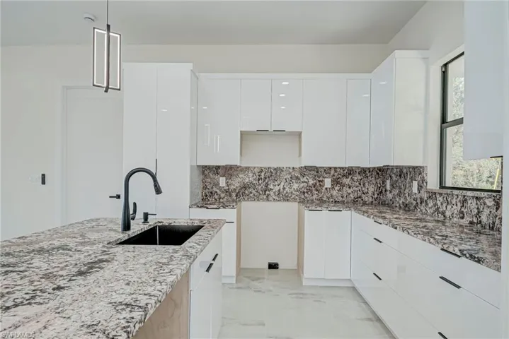 Kitchen featuring white cabinets, modern cabinets, and light stone countertops