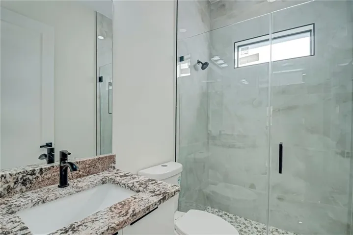 Bathroom featuring vanity and a marble finish shower