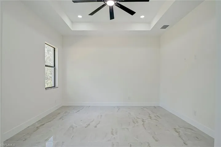Spare room with a raised ceiling, recessed lighting, and ceiling fan