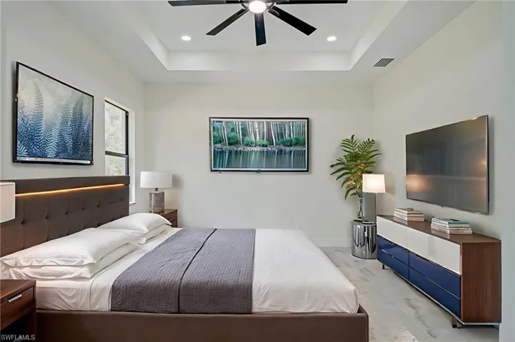 Bedroom featuring a tray ceiling, a ceiling fan, wood finished floors, and recessed lighting