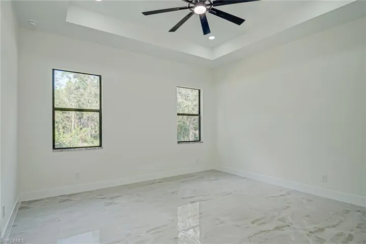 Spare room featuring a tray ceiling, recessed lighting, and a ceiling fan