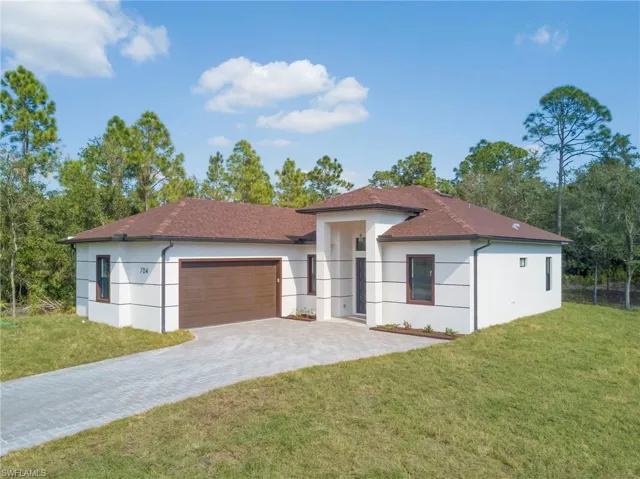 View of front of property featuring a front lawn, decorative driveway, and stucco siding