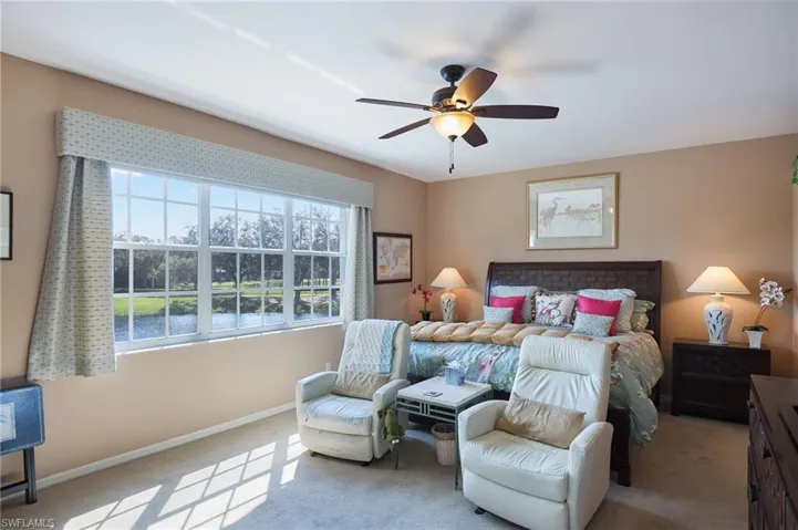 Bedroom with light colored carpet, a water view, and a ceiling fan