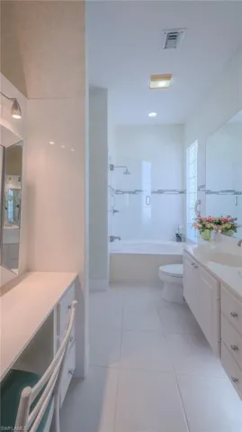 Full bath with vanity, light tile patterned floors, and tile walls