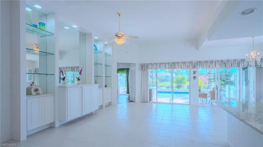 Empty room featuring built in shelves, ceiling fan, light tile patterned floors, and ornamental molding