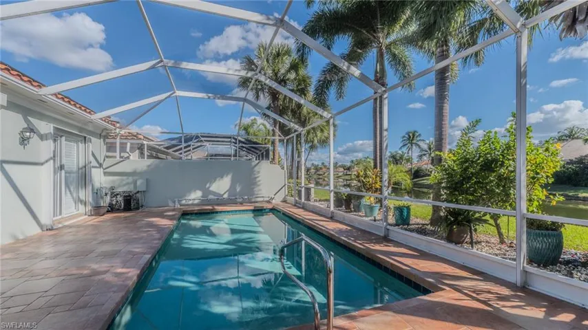 Outdoor pool with glass enclosure, a sunroom, and a patio