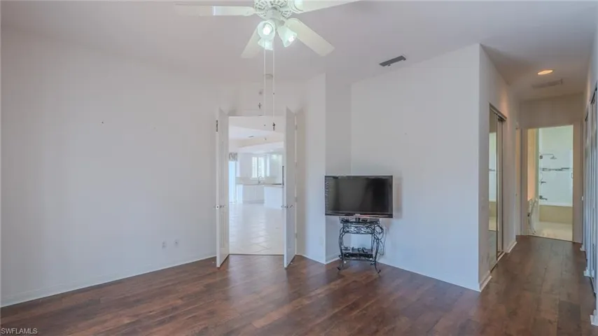 Unfurnished living room featuring dark wood-type flooring and ceiling fan