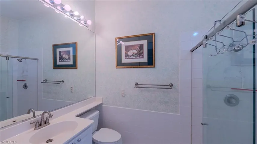 Bathroom featuring vanity, wainscoting, a stall shower, and tile walls