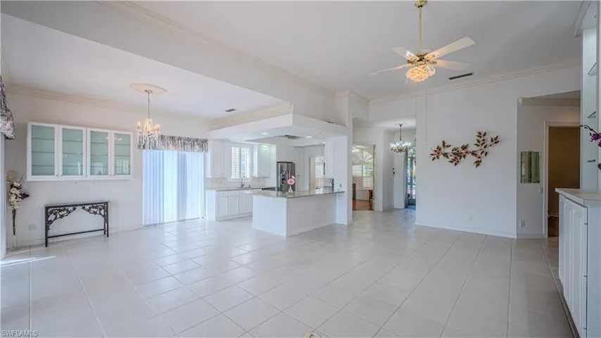 Unfurnished living room featuring a chandelier, a ceiling fan, crown molding, and light tile patterned floors