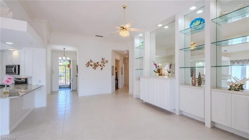 Kitchen featuring white cabinetry, light stone countertops, a ceiling fan, crown molding, and appliances with stainless steel finishes