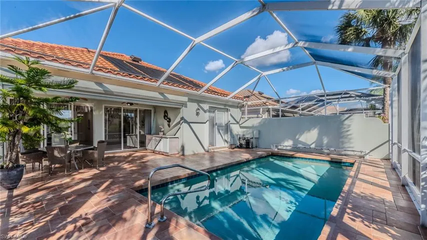 View of swimming pool with a sunroom, glass enclosure, a patio, and outdoor dining area