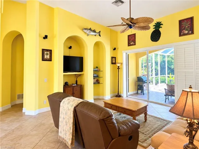High ceilings featuring a palm-leaf style ceiling fan, two arched recessed wall niches, tile flooring, and oversized sliding glass doors