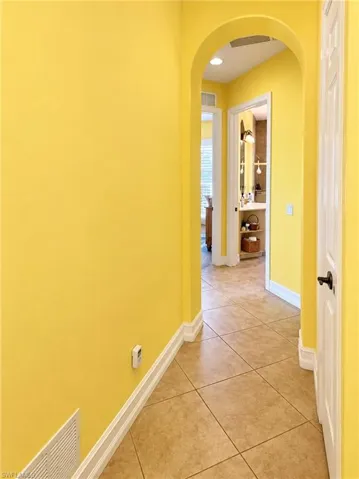 Hallway featuring ceramic tile flooring, arched architectural opening, and recessed ceiling lighting
