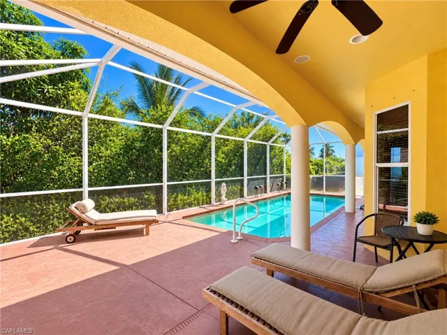 Covered lanai with tile flooring, recessed ceiling lighting, a mounted ceiling fan, and a screened enclosure surrounding an in-ground pool